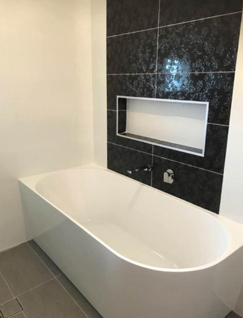 Bathroom renovation with a freestanding bath against marble tiling and brushed gold tapware