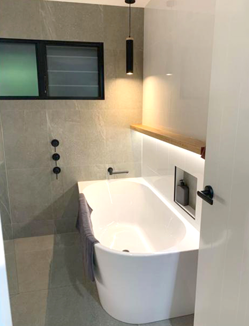 Bathroom renovation with freestanding bath, chrome tapware and timber shelf
