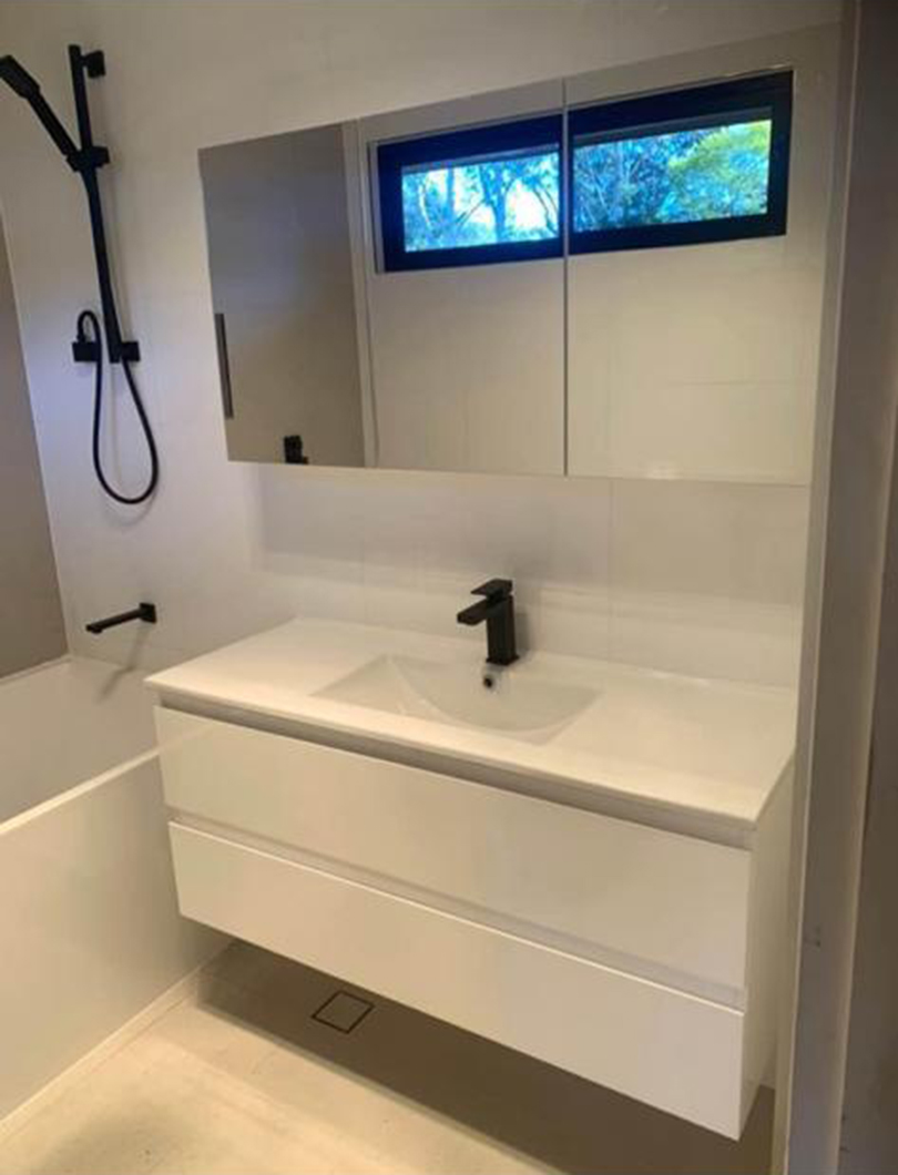 Bright white bathroom renovation with black tapware and garden window